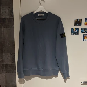 Blå sweatshirt från Stone Island - Säljer en stilren blå sweatshirt från Stone Island med klassisk patch på vänster ärm. Tröjan har rund halsringning och långa ärmar. Knappast använd då den är för liten för mig . Haft den på mig ca 6 gånger. Så skicket är väldigt bra. 110% äkta , köpt på NK i Göteborg.
