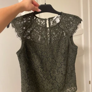 Olivgrön spetsblus från H&M - Olivgrön blus i spets från H&M. Perfekt att styla med jeans eller kjol!