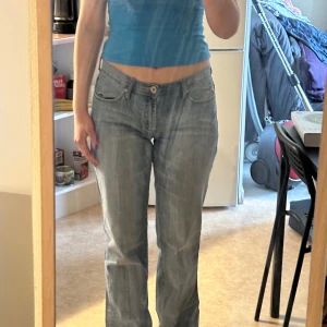 Ljusblå jeansbyxor med normal passform - Säljer ett par klassiska ljusblå jeansbyxor med normal passform och raka ben. Byxorna har fem fickor, knapp och dragkedja framtill samt diskreta slitningar för en avslappnad look. Perfekta till vardags och lätta att matcha med olika toppar.