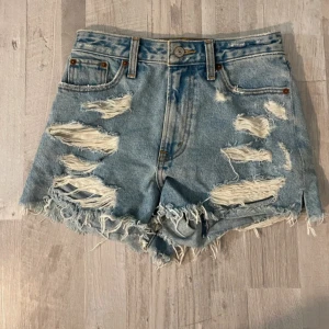 Ljusblåa jeansshorts  - Säljer ett par ljusblå jeansshorts med slitna snygga detaljer och fransig nederkant. Shortsen är knappt använda!
