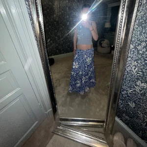 Blåvit blommig långkjol( köpt för 650) - Säljer en blåvit långkjol med stort blommigt mönster. Kjolen har en flowy passform och är perfekt för dig som gillar en avslappnad men ändå snygg stil. Materialet känns lätt och luftigt.