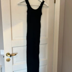 Svart långklänning med breda axelband - Säljer en stilren svart långklänning med breda axelband och rundad halsringning. Klänningen har en tight passform. Aldrig använd, normal i storleken