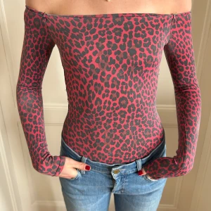 Rosa leopardmönstrad body - Snygg offshoulder body med rosa och svart leopardmönster. Tight passform och långa ärmar. Från Bershka, har ingen lapp men skulle säga storlek XS/S