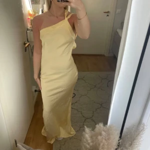 Ljusgul långklänning  - Gul klänning i satin med öppen rygg