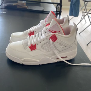 Nike Air Jordan 4 Retro White/Red - Säljer ett par fräscha Nike Air Jordan 4 Retro i vitt skinn med röda detaljer och klassisk Jumpman-logga. Knappt använda och inga större problem med skorna storlek 45