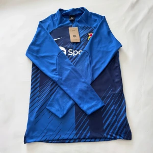 FC Barcelona långärmad träningströja – säsongen 2023/2024 – Storlek S - FC Barcelona långärmad träningströja från säsongen 23/24. Perfekt för träning, uppvärmning eller vardag. Bekväm passform med dragkedja och broderad klubbsköld. Storlek S – passar 165–175 cm och 50–70 kg. Helt ny med tagg. Skicka gärna ett meddelande till mig om du har några frågor!