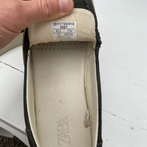 Mörkgrå mockaloafers från Zara - Säljer ett par mörkgrå loafers från Zara i mocka med vit sula. Skorna har en stilren design utan snörning och en mjuk innersula för extra komfort. Perfekta för en avslappnad men snygg look.