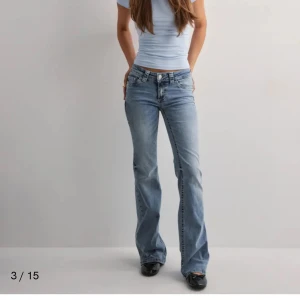 Ljusblå bootcut jeans med broderade bakfickor - Säljer ett par ljusblå bootcut jeans med snygga broderade detaljer på bakfickorna. Jeansen har låg midja och en lätt utsvängd passform nertill. Perfekta för en avslappnad och trendig look.