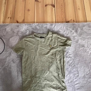 Ljusgrön t-shirt från Lyle & Scott - Snygg ljusgrön t-shirt från Lyle & Scott Junior med klassisk rund hals och liten broderad logga på bröstet. Perfekt för en avslappnad stil och enkel att matcha med jeans eller shorts.