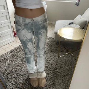 Ljusgrå jeansbyxor med tryckt motiv - Unika ljusgrå jeansbyxor från Gusse med tryckt motiv av ansikten framtill och baktill. Byxorna har normal passform, raka ben och klassisk knappgylf. Så fina och Coola