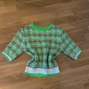 Grön och vit stickad tröja med rutigt mönster - Säljer en unik stickad tröja i grönt och vitt med rutigt mönster. Tröjan har rund halsringning, trekvartsärm och ribbade muddar i grönt och vitt. Perfekt för dig som vill sticka ut med färg och mönster!
