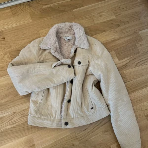 Beige manchesterjacka med teddyfoder  - Säljer en beige manchesterjacka från pull and bear med mysigt teddyfoder. Jackan har krage, knappar framtill och är croppad i modellen. Perfekt för kyligare dagar och ger en trendig look.