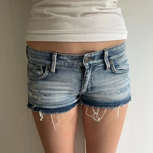 Ljusblå jeansshorts från & Now - Säljer ett par ljusblå jeansshorts från & Now med låg midja och råa fransar nertill. Shortsen har klassisk femficksdesign och slitna detaljer framtill för en cool look. Perfekta för varma dagar! Väldigt fint skick💓💓