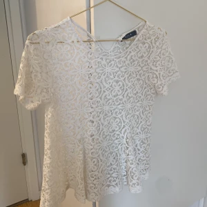 Vit spetsblus från Vila - Säljer en superfin vit spets blus från Vila i storlek Xs. Den har ett väldigt fint mönster. Blusen har korta ärmar och rund halsringning. Perfekt att styla med jeans eller kjol för en fräsch look! Säljer för att den är för stor. Är i jätte bra skick