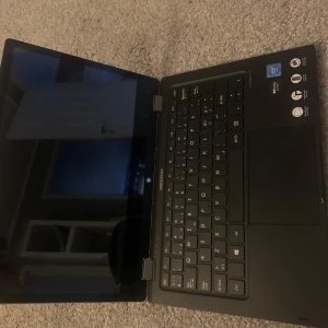 Medion bärbar dator 2-i-1 - Säljer en silverfärgad Medion laptop med 2-i-1-funktion, vilket innebär att den kan användas både som laptop och surfplatta. Datorn har svart tangentbord, stor touchpad och flera portar på sidan, inklusive USB och microSD. Perfekt för studier eller arbete.. finns ingen laddare till då den är trasig därför är den död!!!