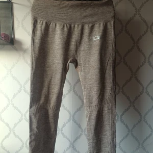 Beige träningtights från ICANIWILL - Snygga beige tights från ICANIWILL med seamless design och ribbade detaljer längs benen. Perfekta för träning. Har hög midja och stretchigt material som sitter skönt på kroppen. Diskret logga framtill. Finns tyvärr ingen lapp kvar inuti men skulle gissa på storlek M. 80 kronor!! 