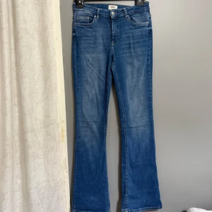Blå bootcut jeans - Snygga blå jeans med bootcut passform och klassisk femficksdesign. Jeansen har normalhög midja och är tillverkade i ett mjukt denimtyg. Perfekta för dig som gillar en tidlös stil med lite utsvängda ben.