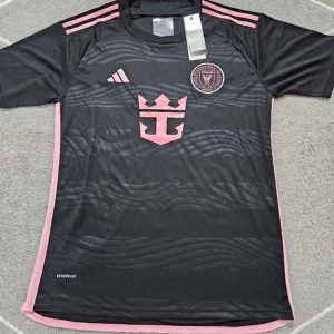 Svart - Inter Miami CF fotbollströja  - Säljer en svart Inter Miami CF fotbollströja från Adidas med rosa detaljer och klubbmärke på bröstet. Tröjan har korta ärmar, rosa ränder på axlarna och sidopaneler samt vågigt mönster på framsidan. Perfekt för fotbollsfans! Vid frågor är det bara att kontakta - obs finns också i storlek L