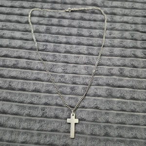 Silverhalsband med kors - Snyggt halsband i äkta silver med en enkel kors. Kedjan är av klassisk modell och berlocken är stämplad med 925 och GHA. Perfekt för dig som gillar stilrena smycken med symbolik.