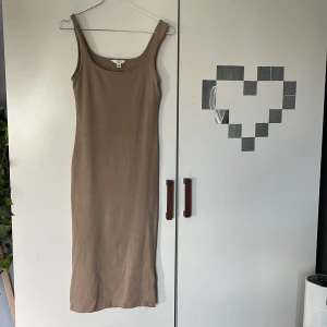 Beige ribbad klänning från H&M - Säljer en enkel och stilren beige ribbad klänning från H&M. Klänningen är ärmlös med rund halsringning och har en tight passform som framhäver figuren. Perfekt att styla med sneakers eller sandaler.