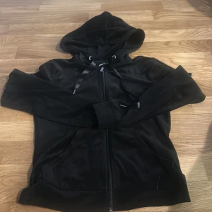 Svart hoodie från Gina Tricot - Svart hoodie från Gina Tricot i storlek XXS. Tröjan har dragkedja framtill, huva med snören och långa ärmar. Perfekt för en avslappnad stil.