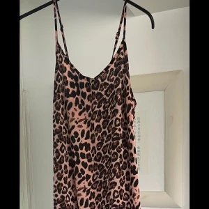 Leopardmönstrad klänning med volang - Säljer en leopardmönstrad klänning med smala justerbara axelband och volang nertill. Klänningen har en lös passform och är i ett mjukt, lätt material som känns skönt mot huden. Perfekt för dig som vill sticka ut med ett djurmönster!