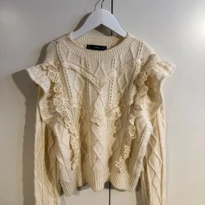 Vit stickad tröja med volang från Mango - Superfin vit stickad tröja från Mango med  volanger och spetsdetaljer längs axlarna. Knappt använd, kostade 600 ny. 