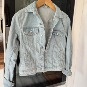 Ljusblå jeansjacka från H&M - Säljer denna fina jeansjacka. Är helt oanvänd, passar perfekt till vår och sommar. Storlek XS