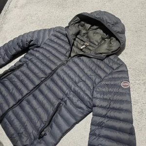 Colmar, mörkblå dunjacka - Säljer en mörkblå dunjacka från Colmar med huva och dragkedja. Perfekt för alla dagar och enkel att matcha med olika outfits.                                Jackan köptes in i höstas och har använts fåtal gånger. Finns inga defekter eller tecken på användning. Jackan är i storlek 50 vilket motsvarar M/L.                                                     Nypris ligger på 2900kr. Priset är ej hugget i sten, hör av dig vid minsta fundering!
