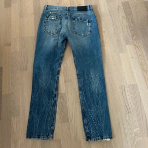 Helmut Lang jeans  - Säljer ett par blå jeansbyxor från Helmut Lang med slitna detaljer och raka ben. Hör av dig om du har frågor eller funderingar! 