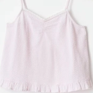 Ljusrosa linnetopp med volangkant från gina - Söt ljusrosa linnetopp med tunna axelband och volangdetalj längst ner. Toppen har en lätt strukturerad yta och en avslappnad passform, perfekt för varma dagar.
