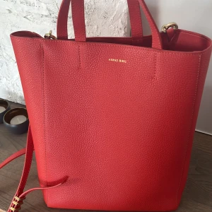 Röd handväska från Anine Bing - Säljer en snygg röd handväska från Anine Bing i präglat skinn. Väskan har både handtag och justerbar axelrem i samma färg samt guldfärgade metalldetaljer. Invändigt finns ett fack med dragkedja för extra förvaring. Perfekt accessoar för att lyfta din outfit. Kan gå ner till 1800!