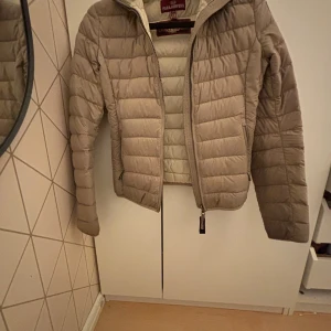 Beige dunjacka från Parajumpers - Säljer en beige, lätt och quiltad dunjacka från Parajumpers. Jackan har lång ärm, dragkedja framtill och klassisk Parajumpers-logga på ärmen. Perfekt för kyliga dagar när du vill ha något smidigt men varmt. Pris är diskutabelt 