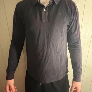 Mörkblå långärmad pikétröja från Tommy Hilfiger - Säljer en klassisk mörkblå långärmad pikétröja från Tommy Hilfiger. 