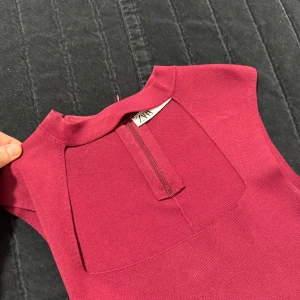 Vinröd ärmlös topp från Zara - Säljer en vinröd ärmlös klänning från Zara med snygg, fyrkantig halsringning och figurnära passform. Klänningen har en stilren design och är perfekt för dig som gillar minimalistiska plagg med modern känsla.