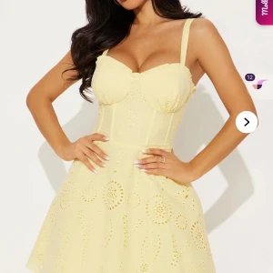 Gul kort klänning med broderade detaljer - Söt gul klänning med markerad byst och breda axelband. Klänningen har broderade mönster och en lätt utsvängd kjol. Perfekt för varma dagar och somriga tillfällen. Helt oanvänd med prislapp kvar.  