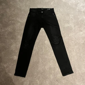 Svarta Replay Anbass jeans - Säljer ett par svarta Replay Anbass jeans som inte används. Modellen är Anbass, storlek 28,30. Superfint skick då de nästan aldrig kommit till användning. Hör av er om minsta lilla fundering💫