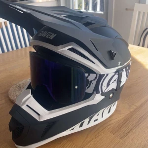 Svart och vit motocrosshjälm från Raven - Säljer en svart och vit motocrosshjälm från Raven med coolt grafiskt mönster och spegelvisir och glasögonen. Knappt använt hjälmen, enbart under förra sommarn. Nypris på dessa två artiklar är 1400kr. Mitt pris 1049kr! Pris går alltid att diskutera! Påse ingår också. Säljes pga. Ingen användning av de. Skriv för flera bilder.