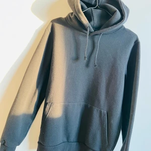Svart hoodie med huva och ficka - En klassisk svart hoodie med huva och dragsko samt en stor magficka. Perfekt för en avslappnad stil och enkel att matcha med det mesta. Mjuk och bekväm, passar både till jeans och mjukisbyxor.