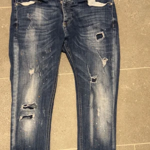 Blå slitna jeans från Kings Will Dream - Säljer ett par blå jeans från Kings Will Dream med slitningar och hål på benen. Jeansen har normal passform, inga defekter och väldigt feta. 
