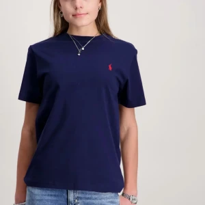 Mörkblå t-shirt från Ralph Lauren - Säljer en klassisk mörkblå t-shirt från Ralph Lauren med röd broderad logga på bröstet. T-shirten har rund halsringning och korta ärmar. Perfekt basplagg till garderoben!har tyvärr ett litet häl på magen men det är ett jatte litet hål