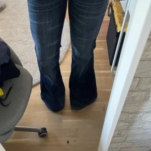 Blå bootcut jeans från Cheap Monday - Säljer ett par blå bootcut jeans från Cheap Monday med klassisk femficksdesign och utsvängda ben. Jeansen har låg midja och är tillverkade i denim. Perfekta för dig som gillar en retroinspirerad look. De har lite slitningar längst ner!