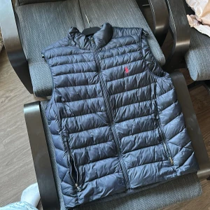 Ralph lauren väst  - Snygg  marinblå dunväst med dragkedja och två praktiska fickor framtill. Perfekt för lager-på-lager under kyliga dagar. Diskret logotyp på bröstet ger en stilren touch.  Priset är inte ristat i Sten så går att diskuteras😊