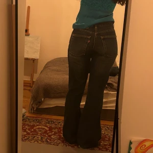 Levis jeans med bootcut - Snygga Levis jeans i mörkblå denim med bootcut-stil. De har en klassisk femficksdesign och en medel midja. Jeansen har en sliten look vid fållen för en trendig touch. Perfekta för en avslappnad stil.