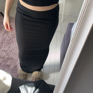 Svart ribbad kjol  - Svart ribbad långkjol med slitt  baktill. 