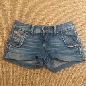 Blå jeansshorts från Diesel - Snygga blå jeansshorts från Diesel med slitna detaljer och klassisk femficksdesign. Perfekta för en avslappnad stil. De har en knapp och dragkedja framtill samt bälteshällor. De är i mycket bra skick och sparsamt använda, midjemått 36cm💕