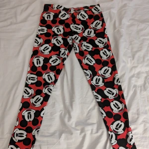 Mönstrade leggings med Musse Pigg - Snygga leggings med ett lekfullt Musse Pigg-mönster i svart, vitt och rött. Perfekta för dig som vill ha en rolig och unik stil. De är stretchiga och bekväma, idealiska för avslappnade dagar. Material 95% bomull, 5% elastan 