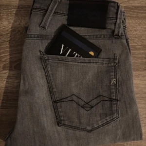 Grå jeans från Replay - Snygga grå jeansbyxor från Replay i modellen Anbass. De har en klassisk femficksdesign och en stilren look. Perfekta för en avslappnad stil med en modern touch.
