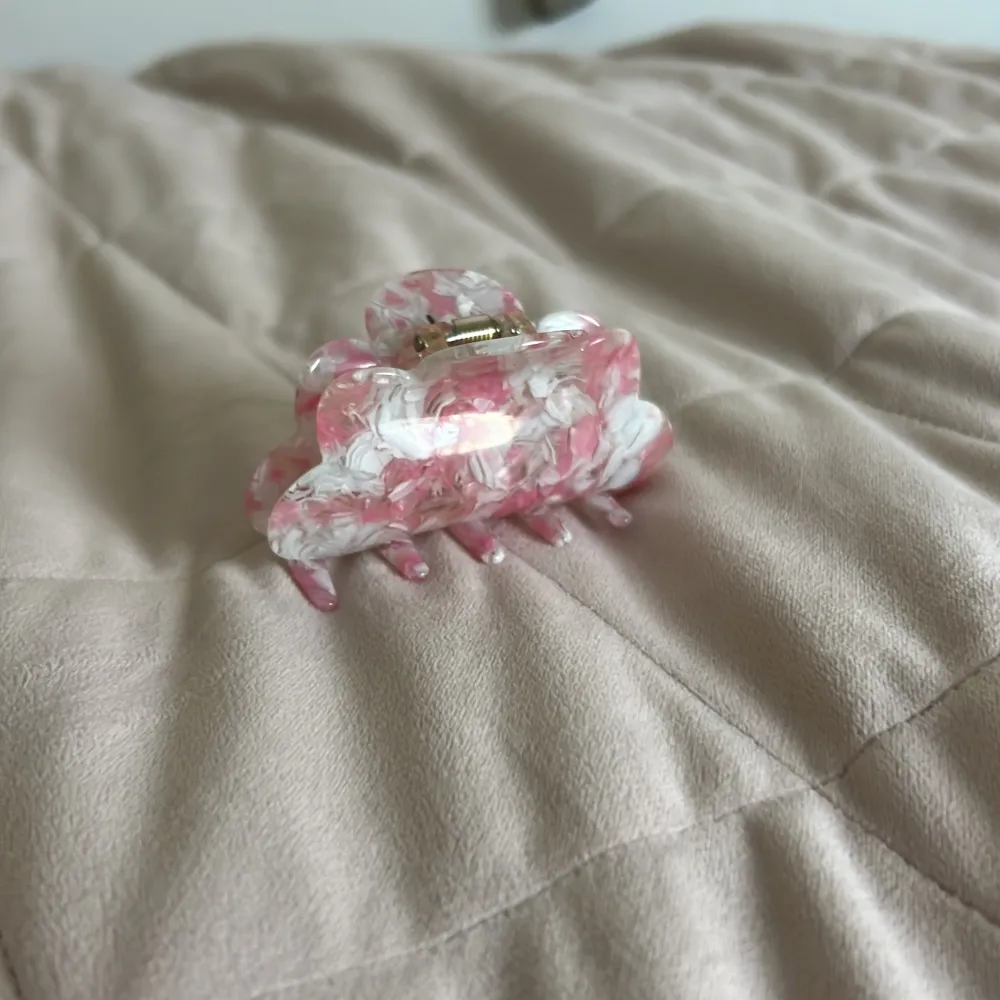 Snygg hårklämma i rosa och vitt med ett marmorerat mönster. Perfekt för att hålla håret på plats med stil. Klämman har en stabil metallfjäder för bra grepp.. Asusteet.