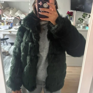 Mörkgrön pälsjacka - Säljer en lyxig mörkgrön pälsjacka med långärmad design. Jackan har en fluffig och elegant look, perfekt för att hålla dig varm och stilren under kallare dagar. Passar utmärkt för höst och vinter.